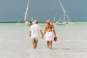 mature couple walking in shallow water to boat