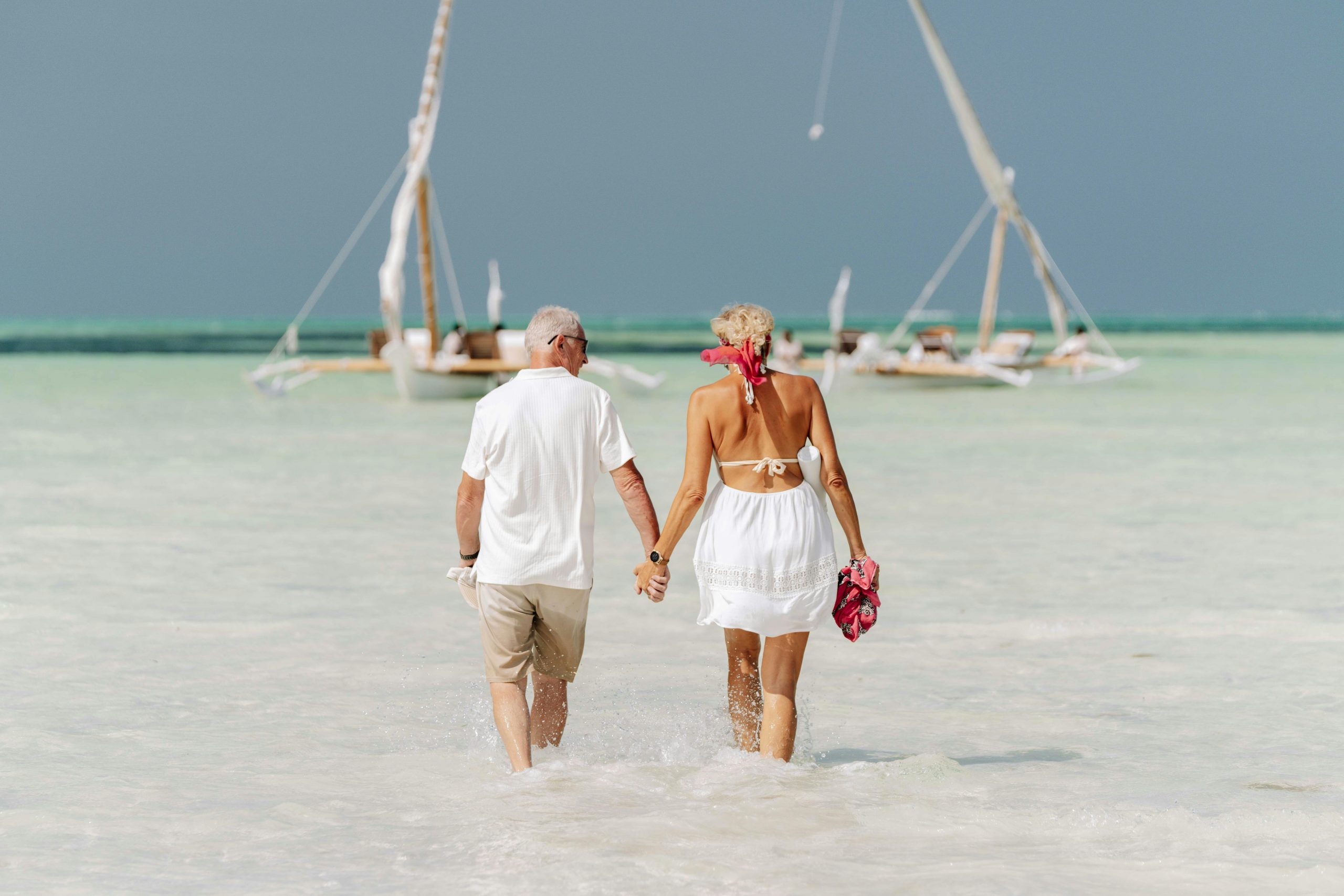 mature couple walking in shallow water to boat